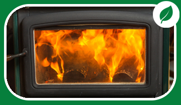 Front of wood stove with flames showing through glass Front of wood stove with flames showing through glass