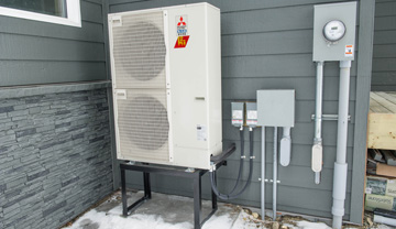 An air source heat pump on the outside wall of a house. An air source heat pump on the outside wall of a house.