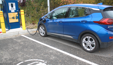 Blue electric car plugged into public charging station Blue electric car plugged into public charging station