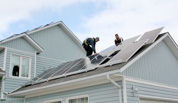 2 tradespeople installing solar panels on a house roof. 2 tradespeople installing solar panels on a house roof.