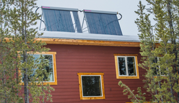 Solar hot-water tubes o the roof of a red house Solar hot-water tubes o the roof of a red house