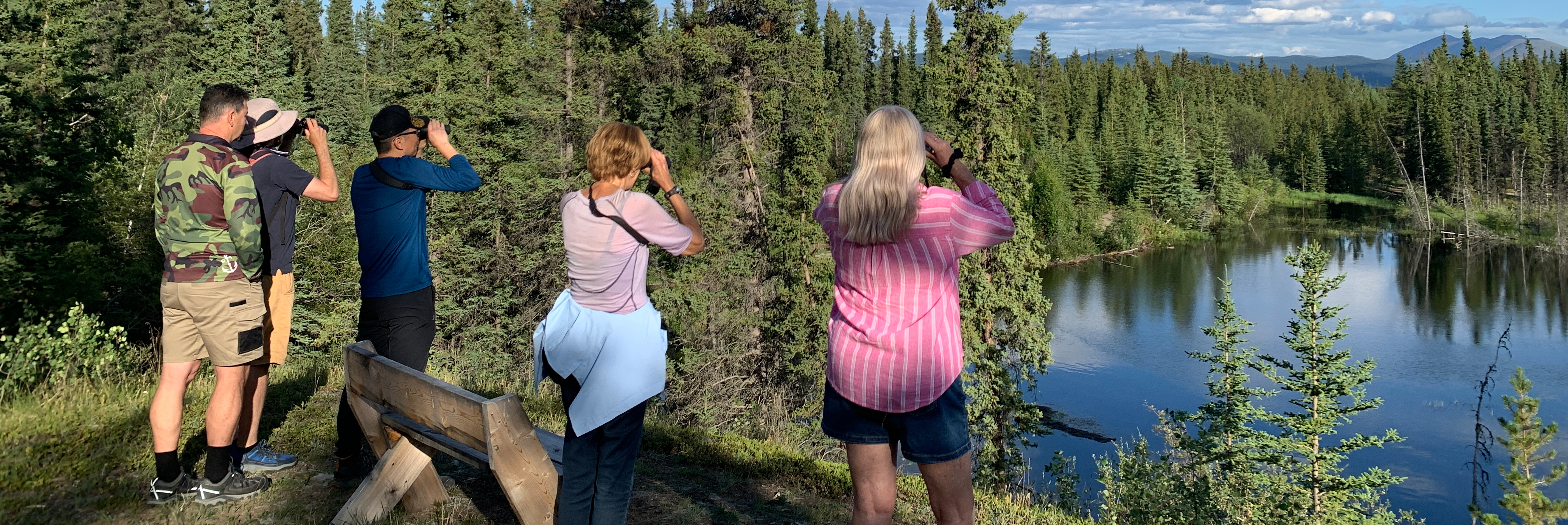 Group of people with binoculars looking over a lake